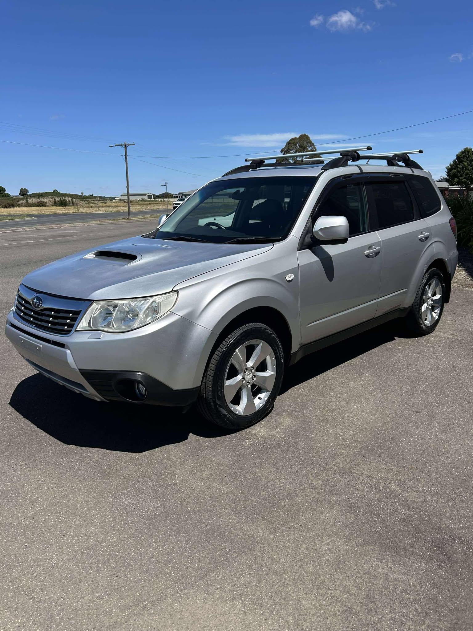 A silver suv is parked in a parking lot on a sunny day.