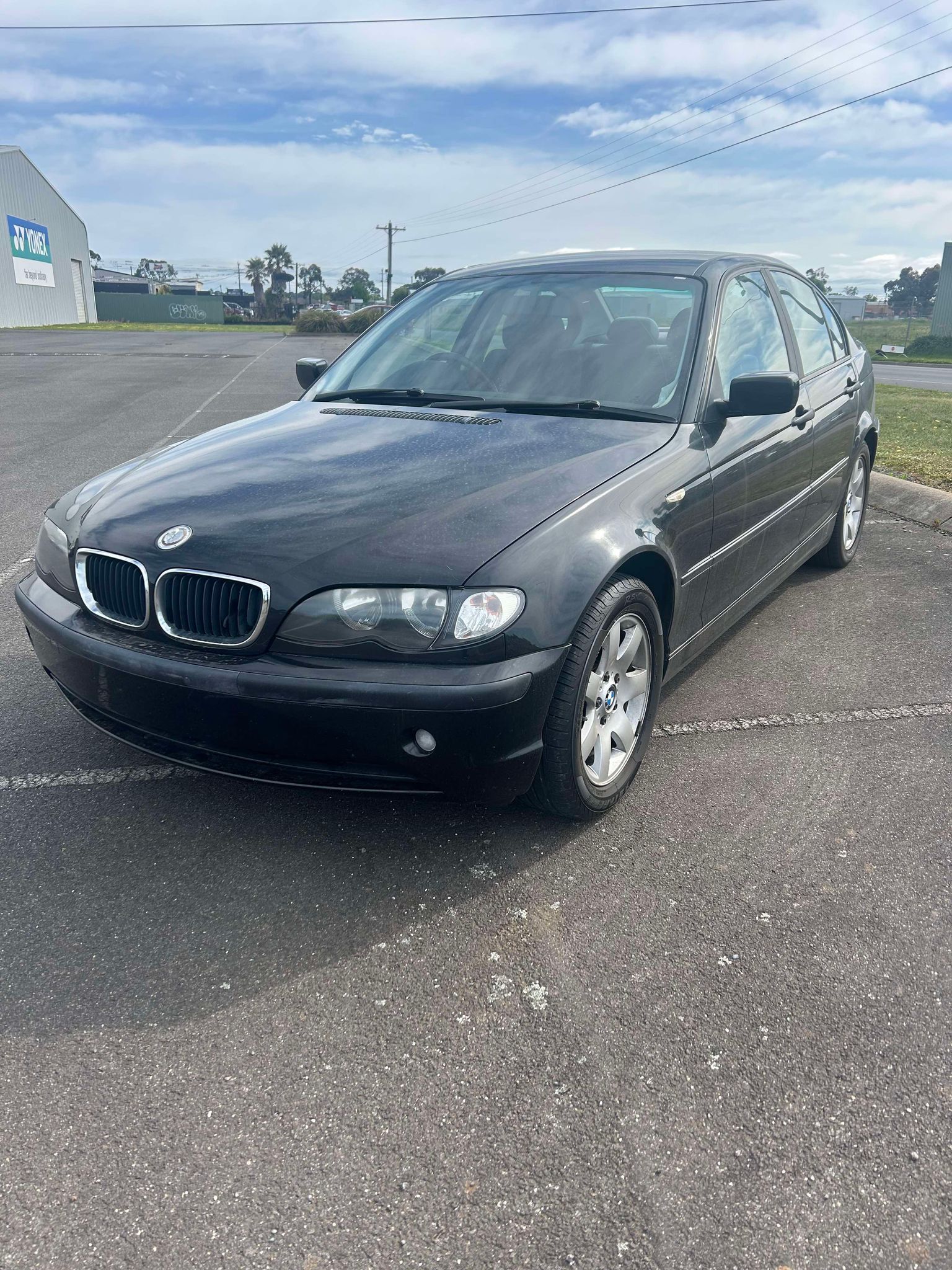 A black bmw is parked in a parking lot.