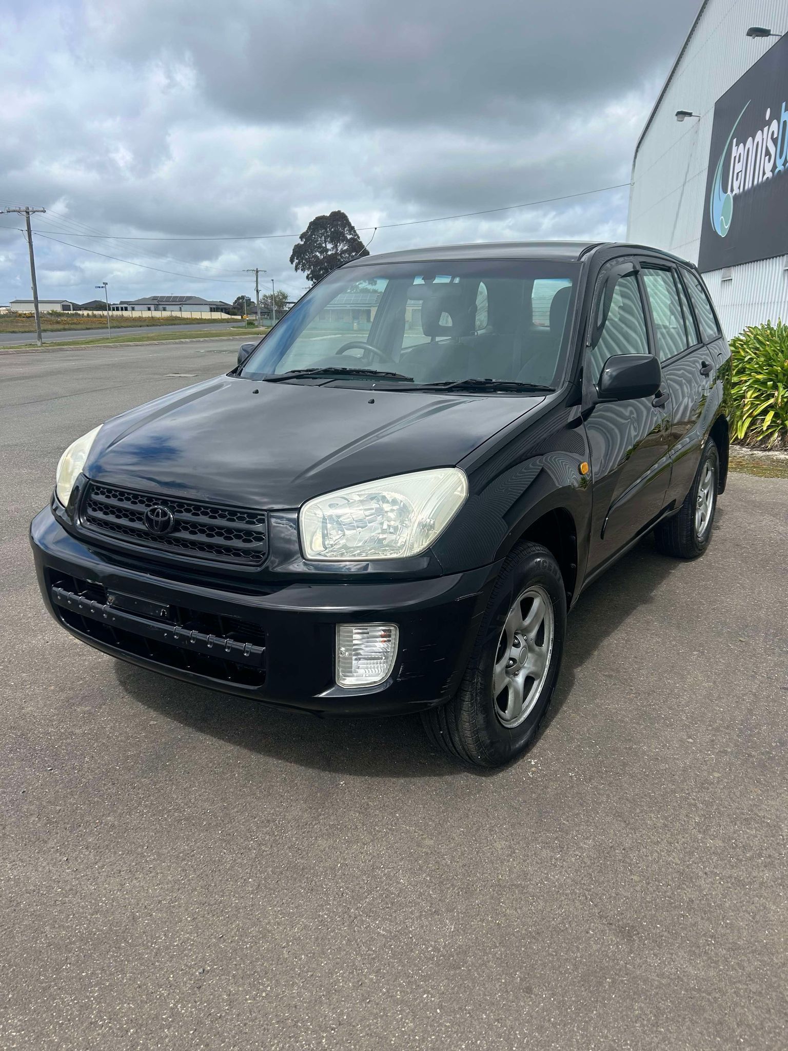 A black suv is parked in a parking lot in front of a building.
