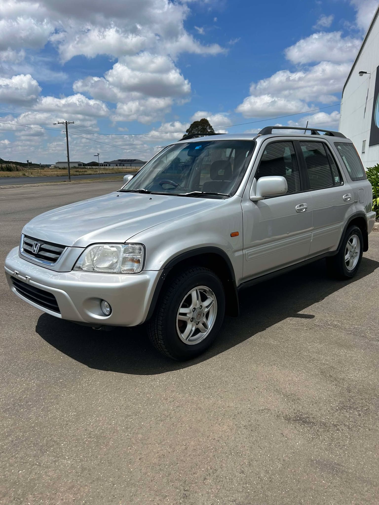 A silver honda cr v is parked in a parking lot.