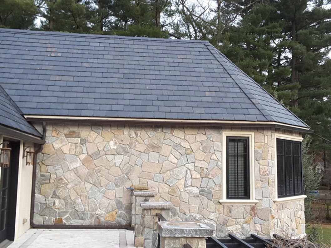A house with a stone wall and a slate roof