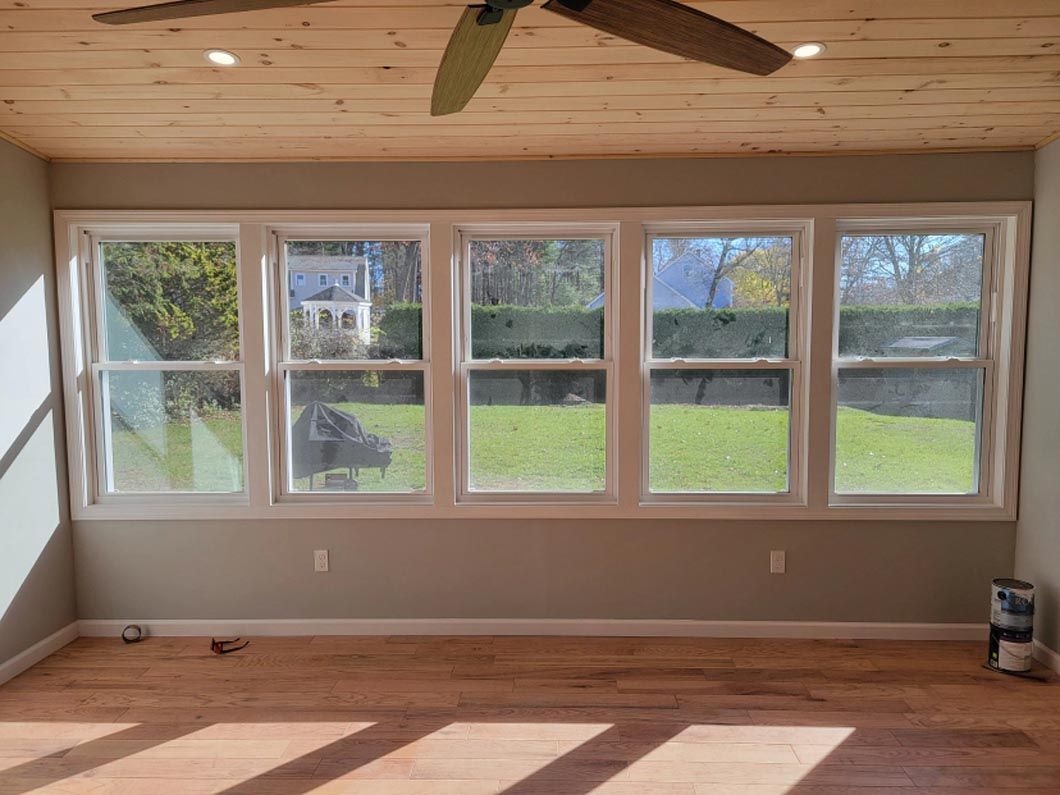 A living room with a lot of windows and a ceiling fan.