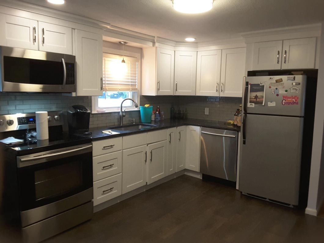 A kitchen with white cabinets , stainless steel appliances and a refrigerator.
