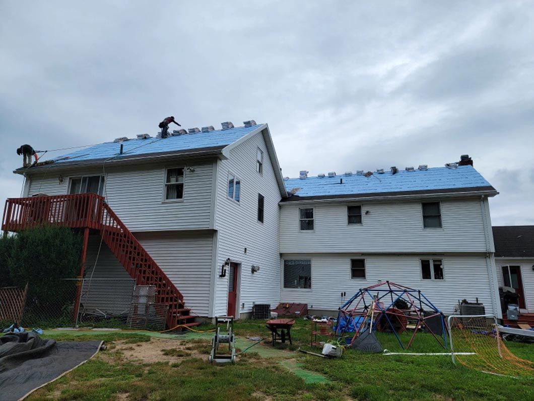 A white house with a blue roof is being remodeled.
