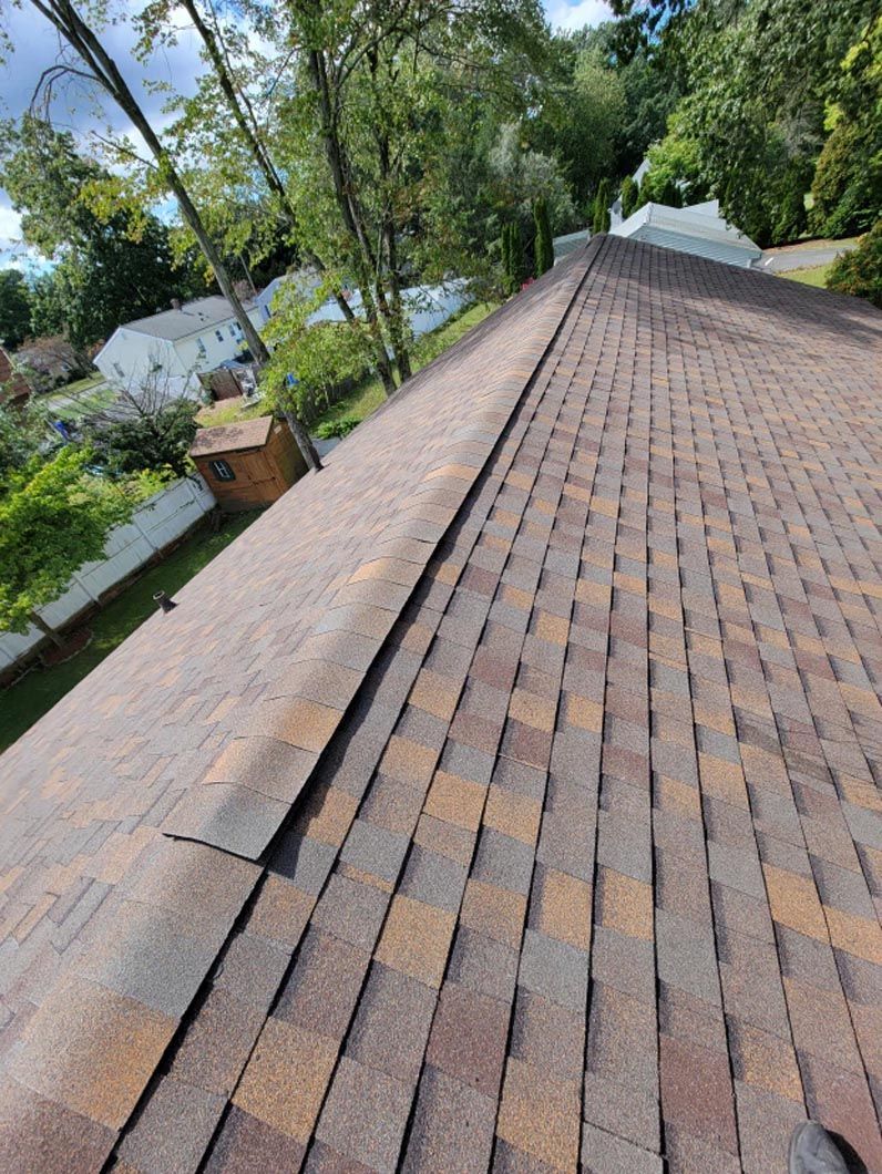 A roof with a lot of shingles on it and trees in the background.