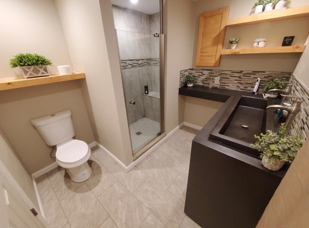 A bathroom with a toilet , sink and shower.