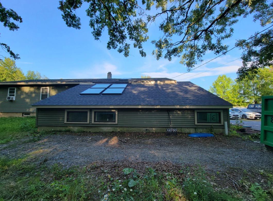 The back of a house with a solar panel on the roof.