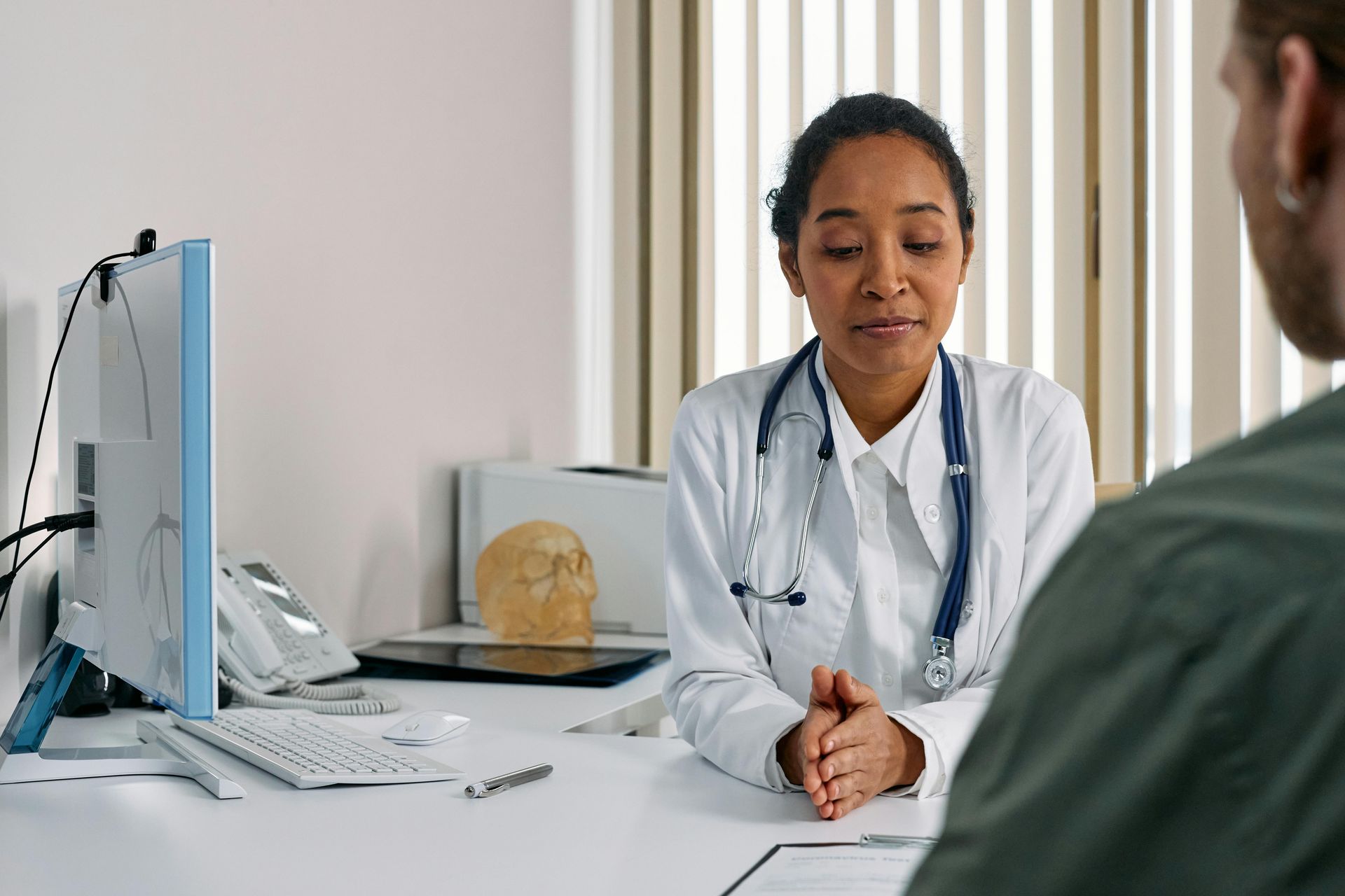 Doctor in white coat speaking to a patient in an office setting.