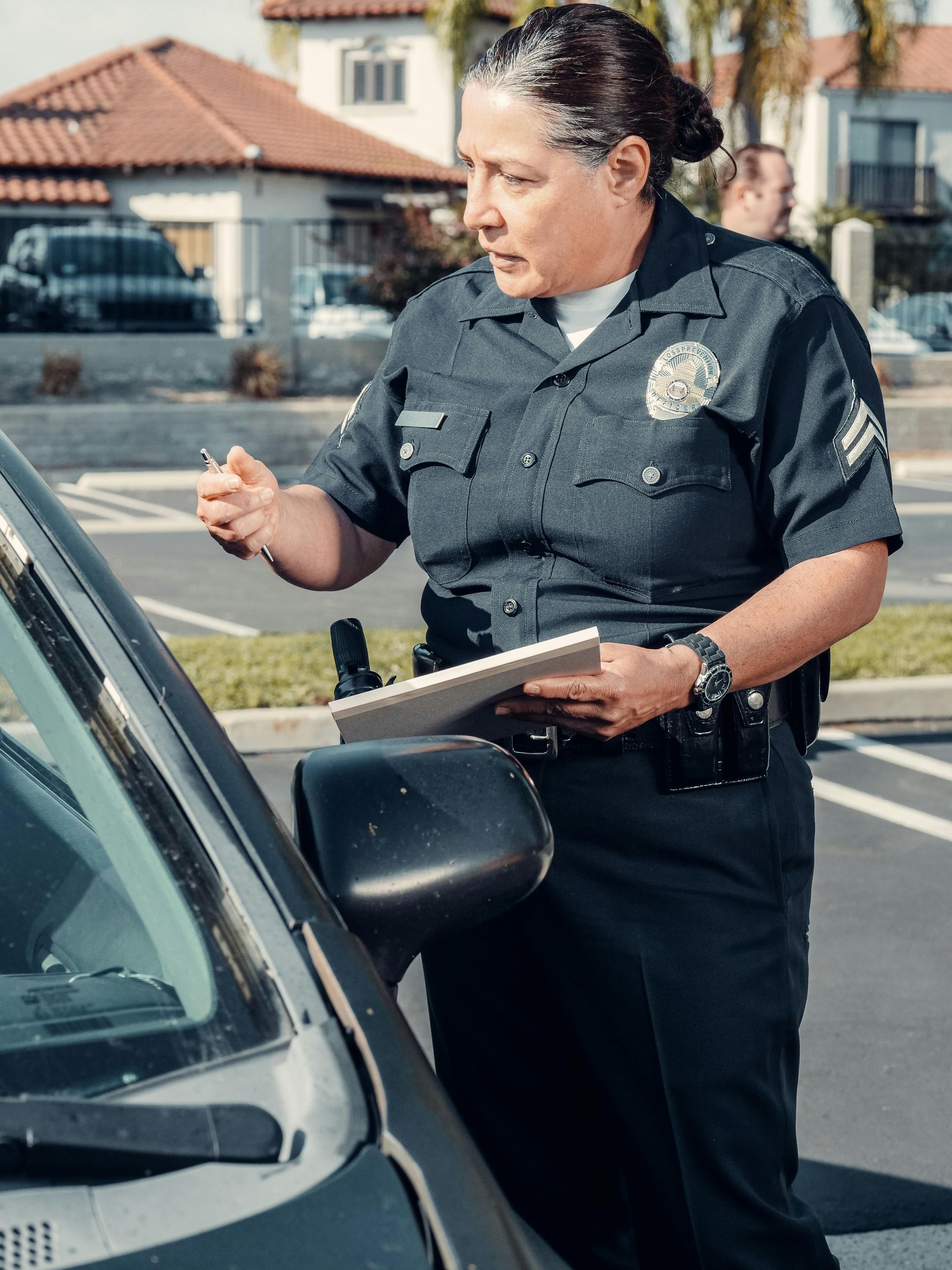Police officer writing a citation next to a car in a residential area.