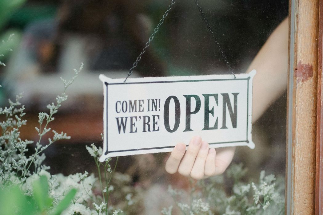 A person is holding a sign that says `` come in we 're open ''.