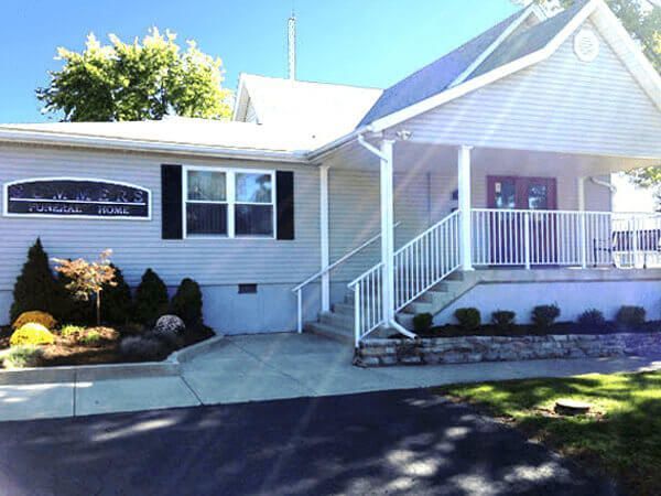 Exterior view of a light blue building with a porch and landscaping.