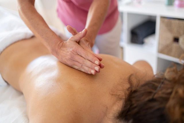 Persona che riceve un massaggio alla schiena in una spa; mani che massaggiano la schiena con olio.
