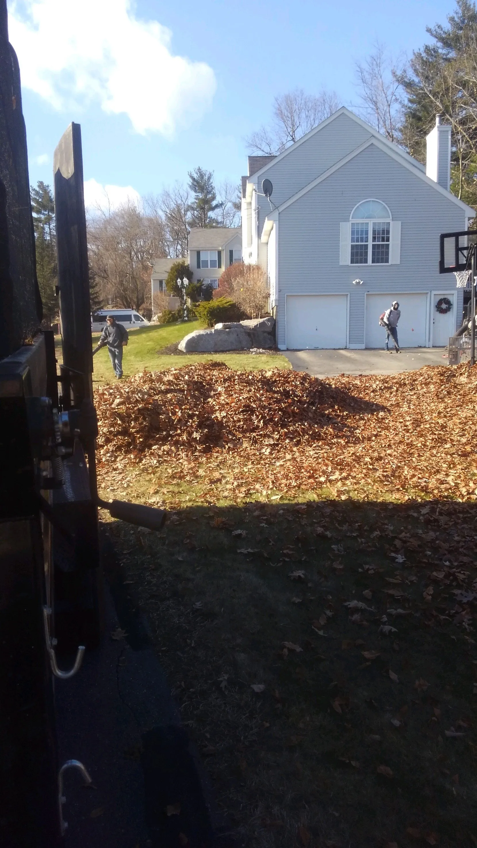 A man is raking leaves in front of a house.