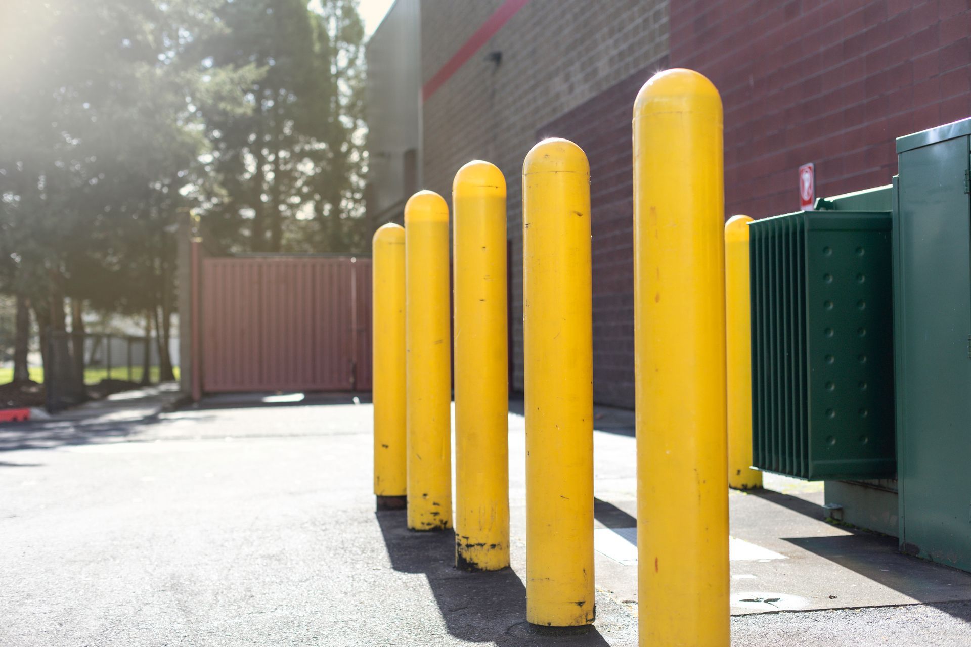 A row of yellow poles are lined up in a parking lot.