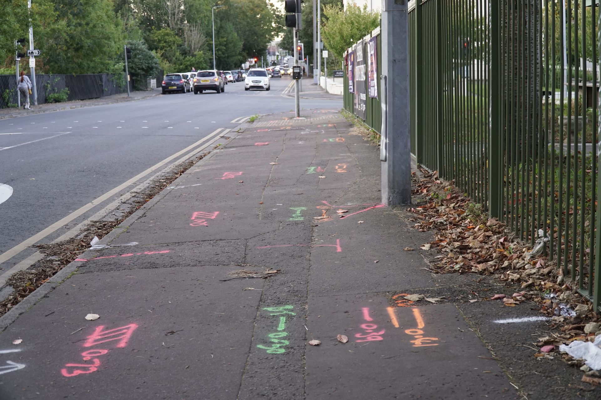 A sidewalk with graffiti on it and a fence in the background.