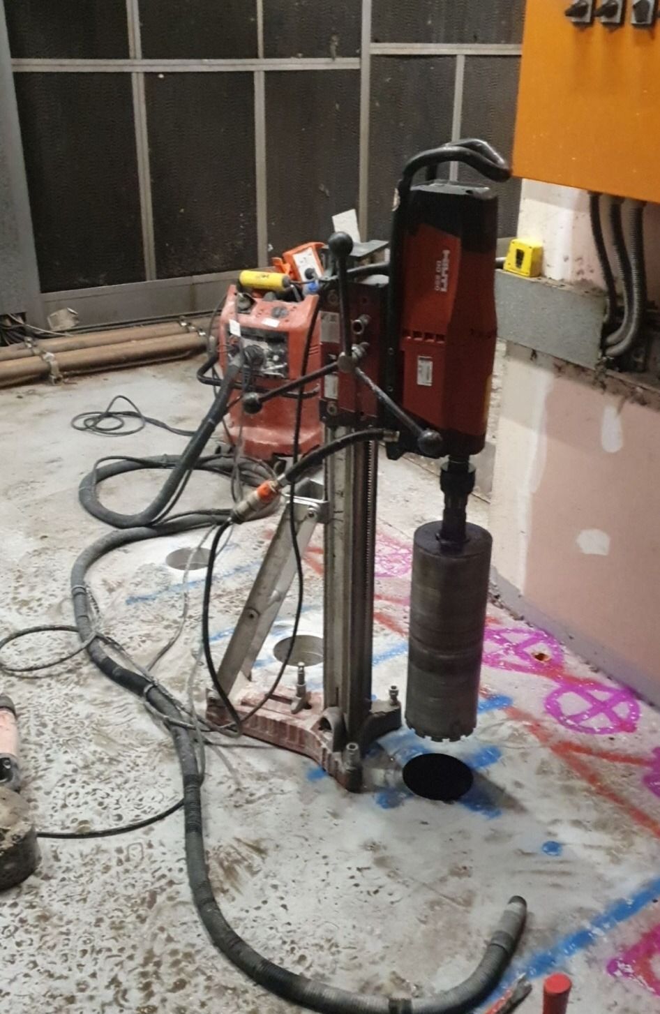A machine is sitting on a concrete floor next to a vacuum cleaner.