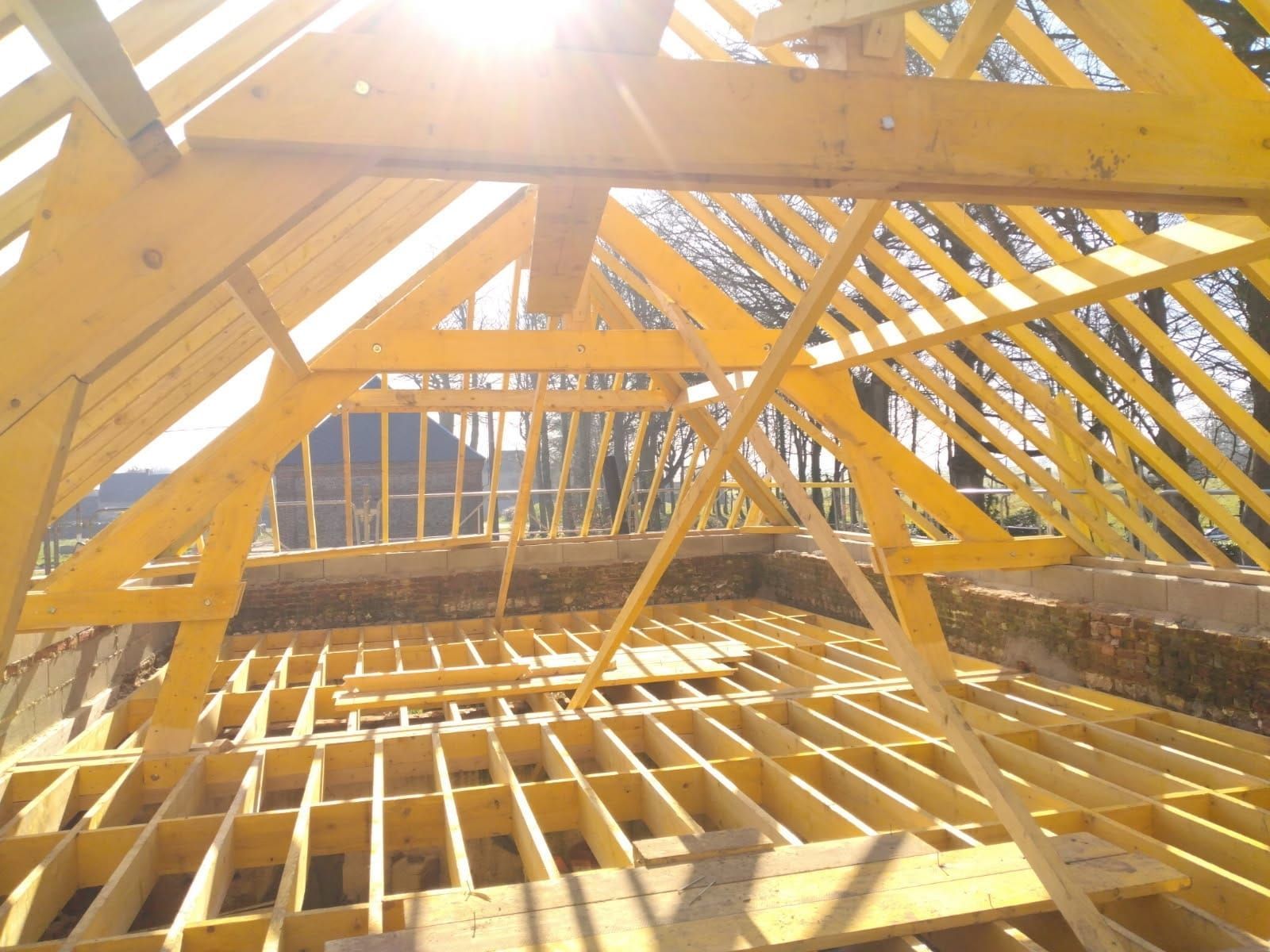 Charpente en bois d'un toit en construction ; lumière du soleil éclatante.