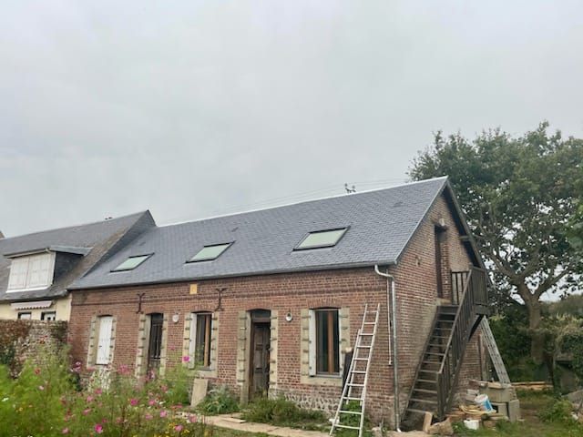 Bâtiment en briques avec un toit en ardoise neuf, des puits de lumière, un escalier en bois et une échelle