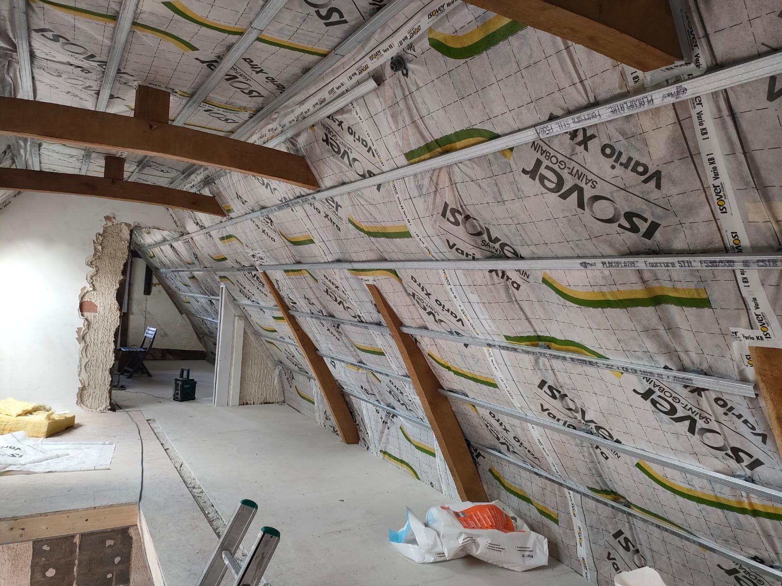 Combles en cours de rénovation avec isolation installée. Poutres apparentes et charpente métallique.