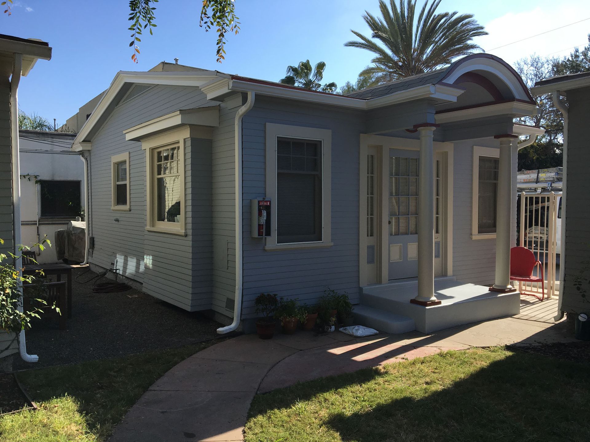 Light blue bungalow with cream trim, front porch, and small yard.