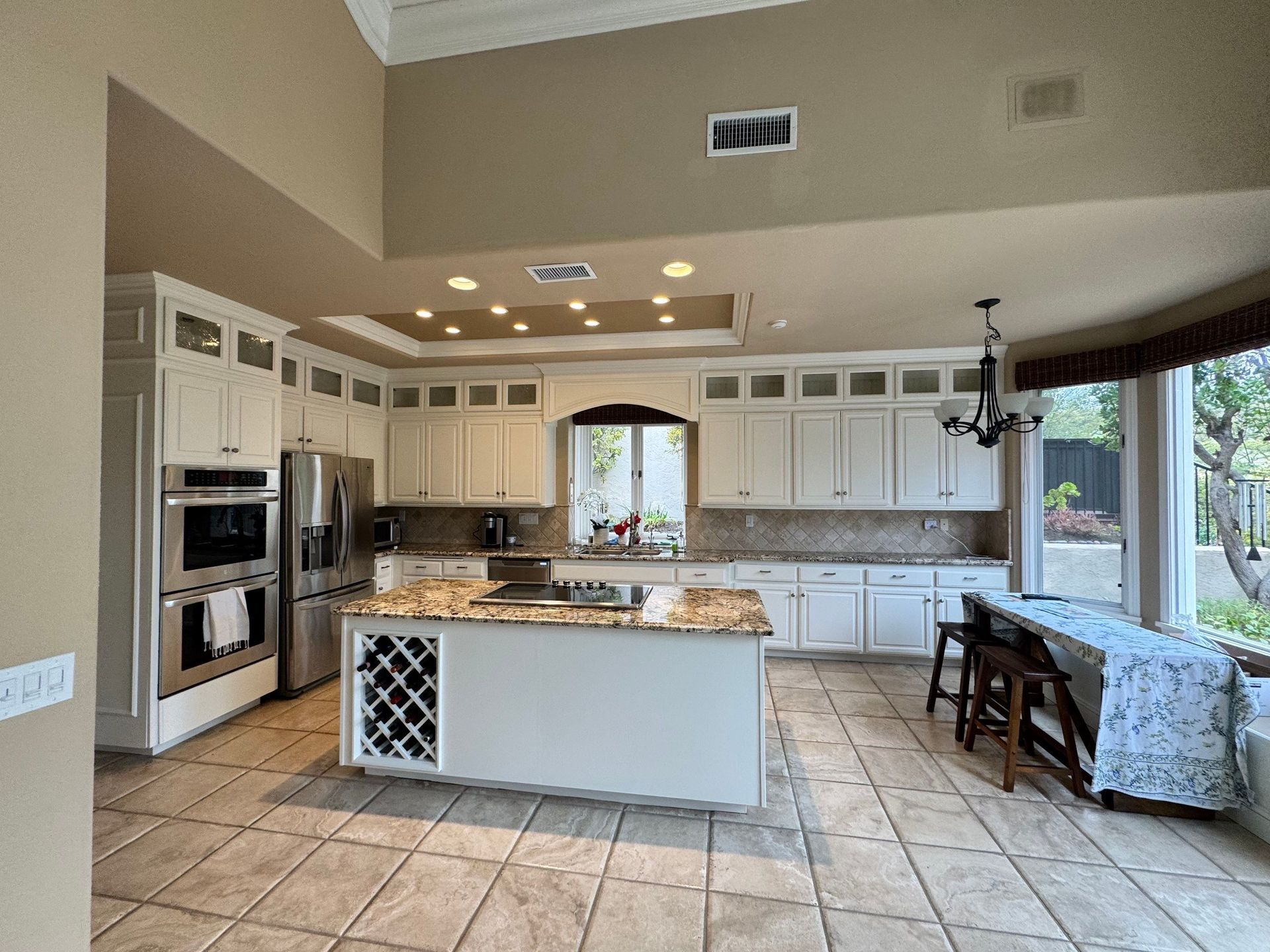 Spacious kitchen with white cabinets, island, stainless steel appliances, and large windows.