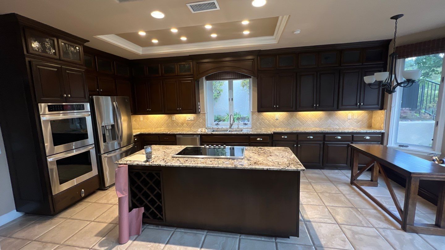 Kitchen with dark cabinets, stainless steel appliances, and an island with granite countertop.