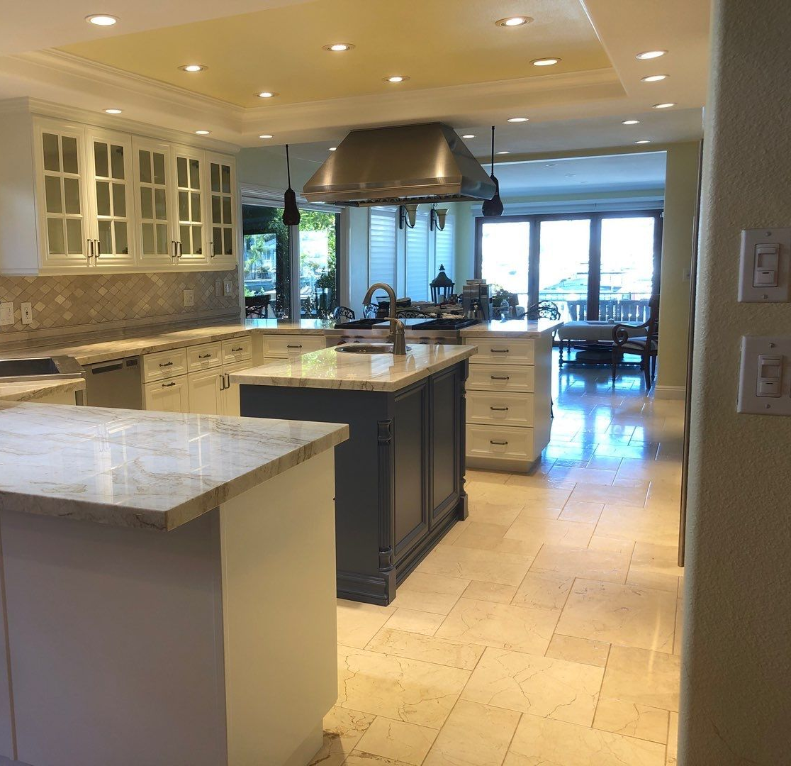 Spacious kitchen with a dark blue island, white cabinets, and granite countertops.