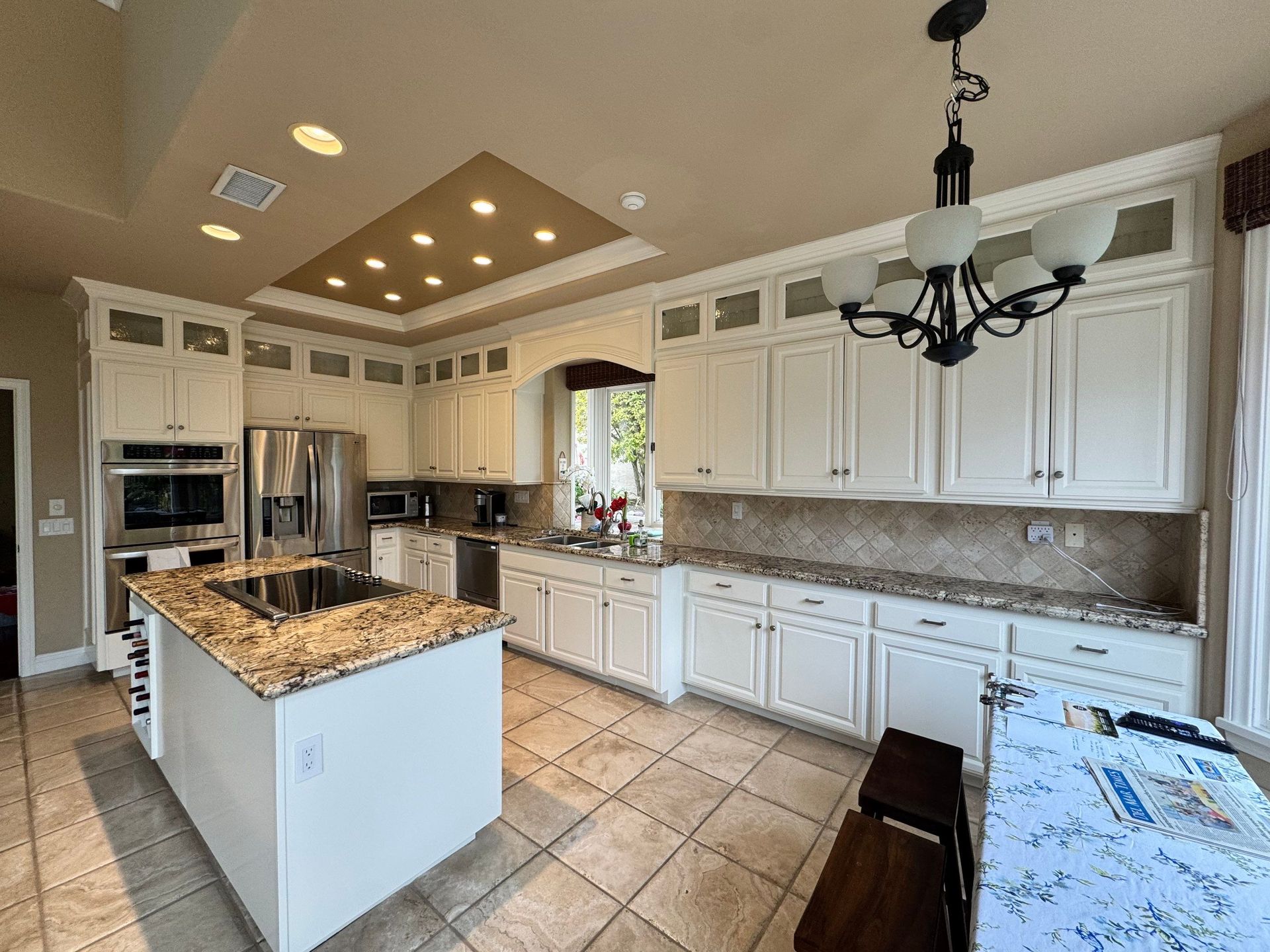 Bright white kitchen with granite countertops, stainless steel appliances, and tile floor.