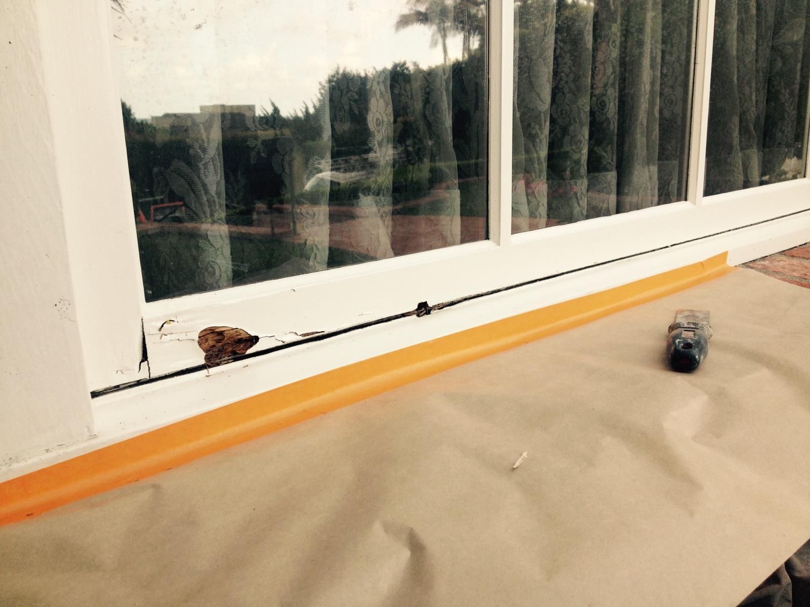 Window frame with masking tape, brown paper, and a paint can.