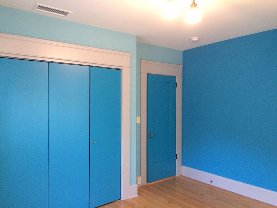 Blue bedroom with matching closet doors, door frame, and walls; white trim, wood floor.