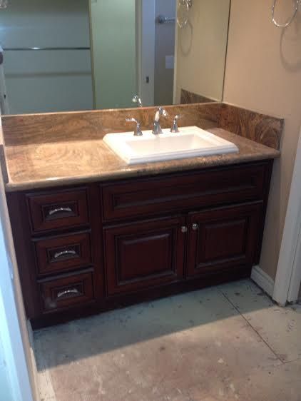 Bathroom vanity with dark brown cabinets, a beige countertop, and a white sink.
