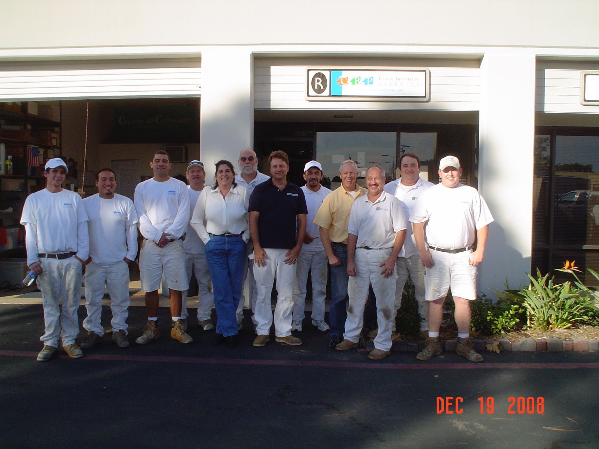Group of people in paint-covered clothes posing in front of a building.