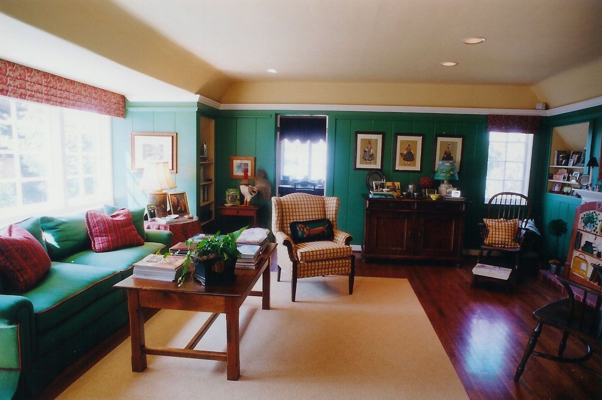Living room with green walls, a green sofa, wooden floors, and a light-colored rug.