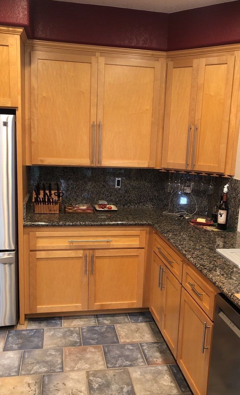 Kitchen corner with light wood cabinets, granite countertops, and tiled floor.