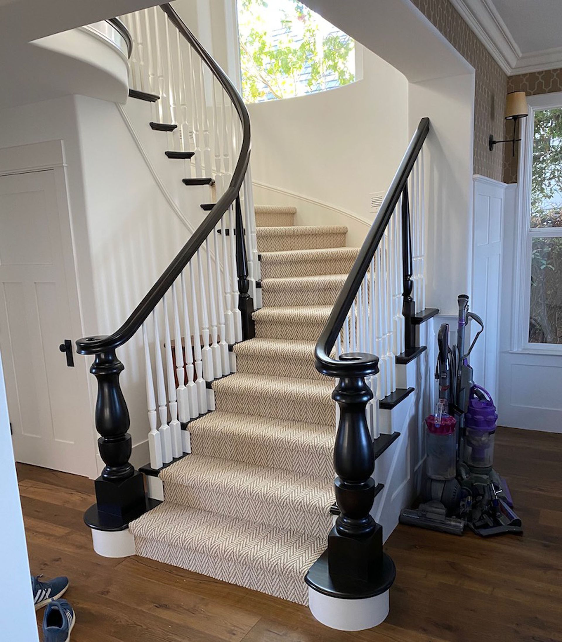 Staircase with carpet runner, white balusters, and black handrails in a home.