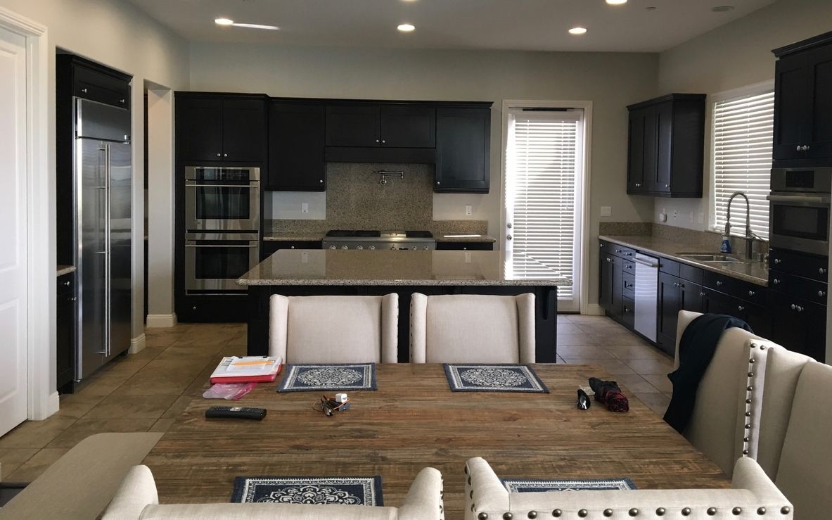 Kitchen with dark cabinets, stainless steel appliances, and a wooden dining table.