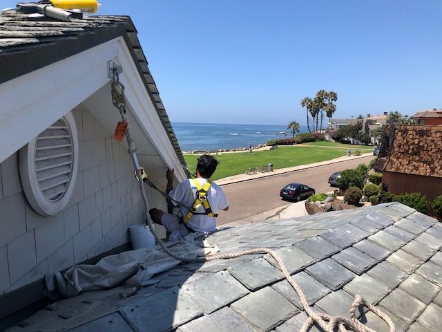 Person on a roof with safety gear, near ocean.