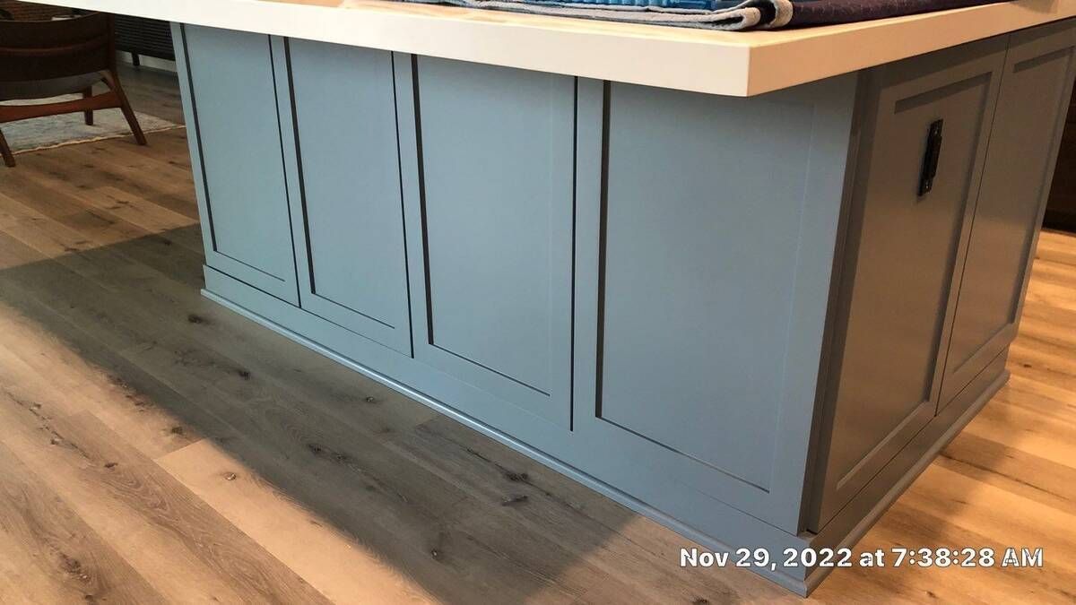 Kitchen island with light blue cabinetry and light countertop.