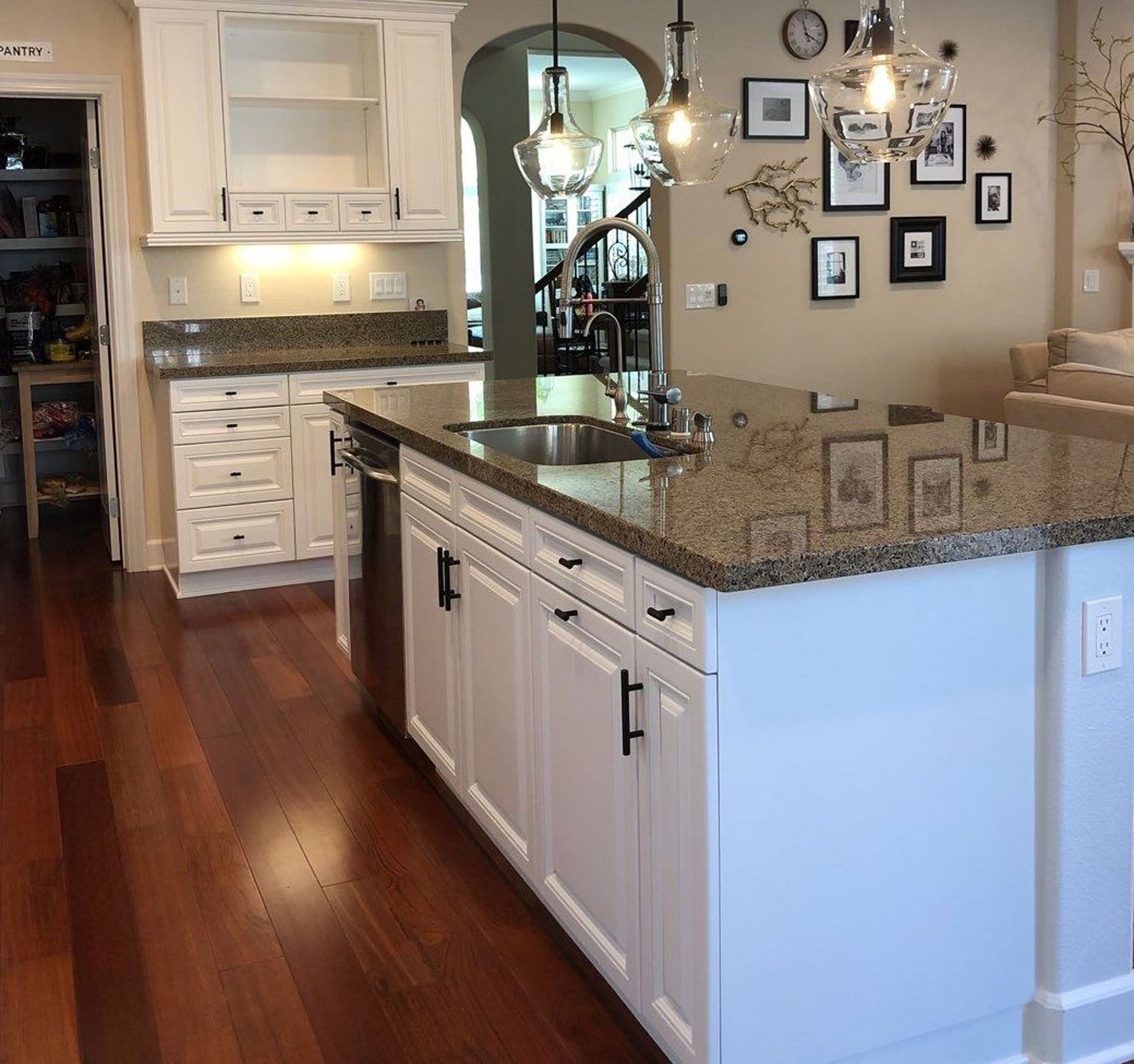 Kitchen with white cabinets, granite countertops, hardwood floors, and a center island.