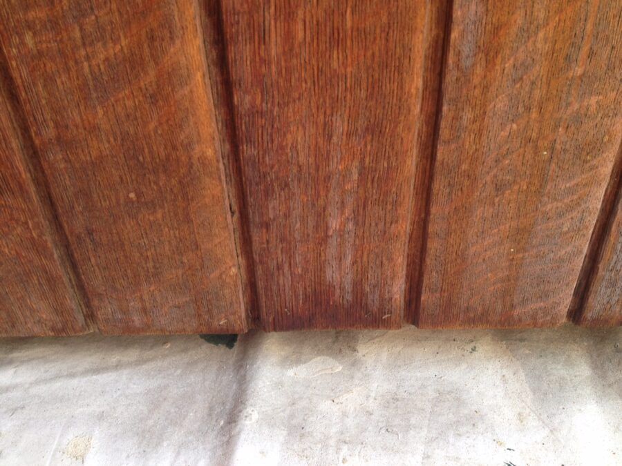 Wooden planks against a light gray concrete surface. Brown wood has vertical grooves and varying tones.
