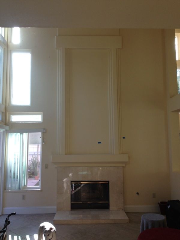 Fireplace with tall, light-colored trim and a marble surround. Large windows let in sunlight.