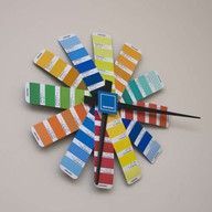 Clock made of colorful paint swatches on a tan wall.