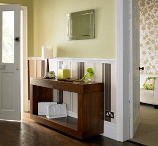 Entryway with wooden console table, mirror, and striped wallpaper.