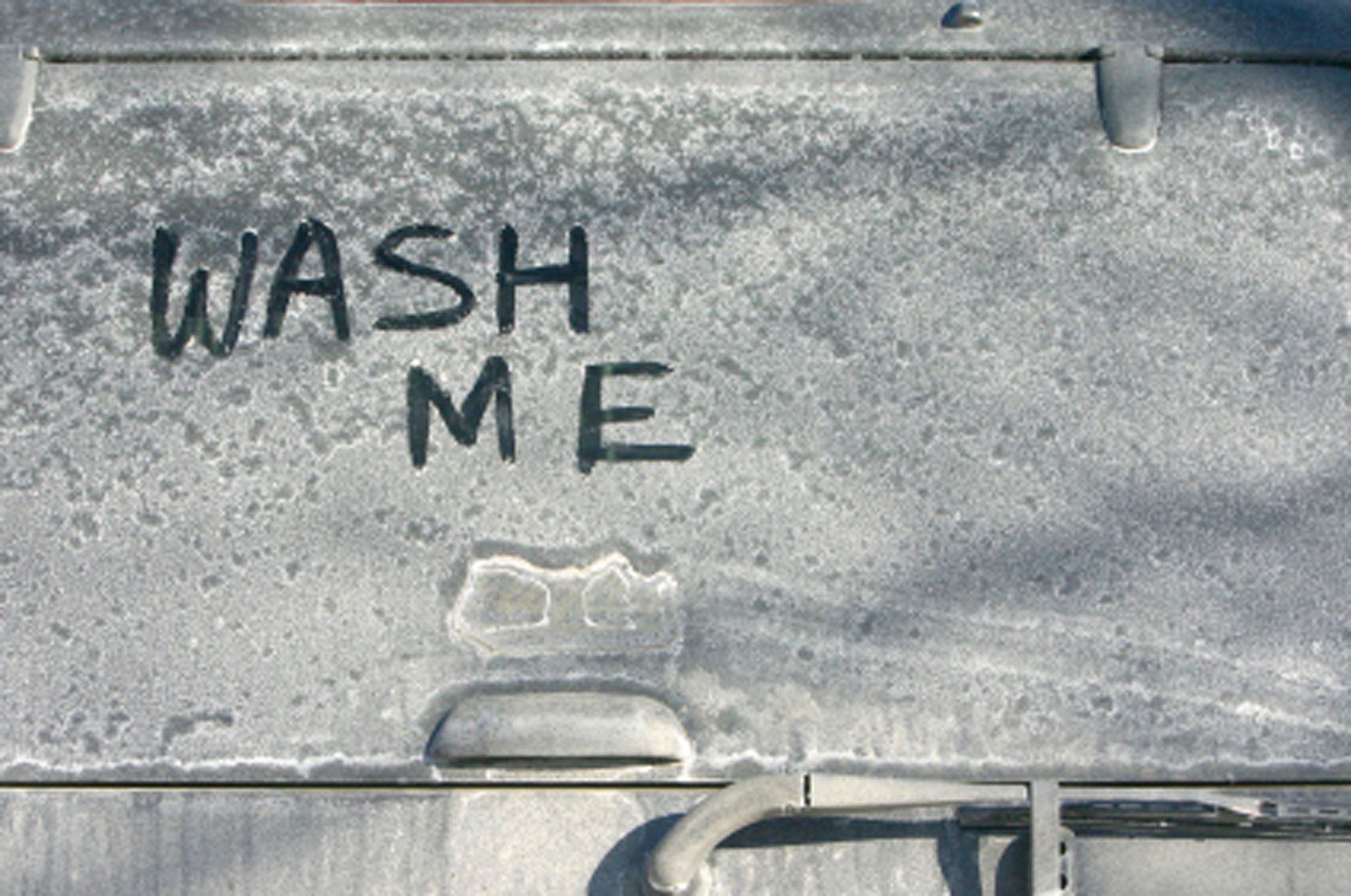 A dirty, dusty gray vehicle door with the words 