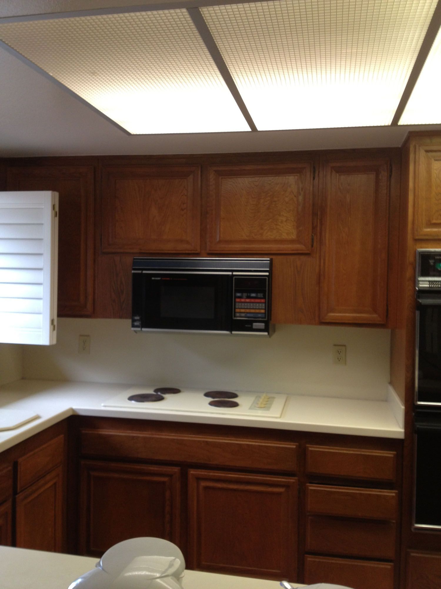 Kitchen with wood cabinets, microwave, and cooktop.