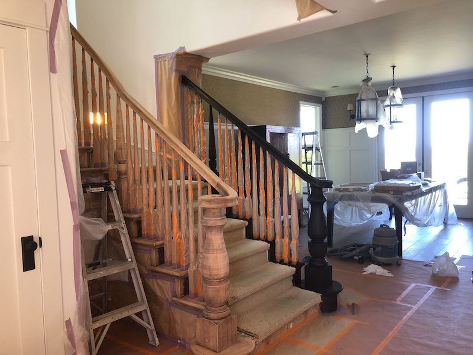 Staircase with wooden balusters, handrail, and steps undergoing renovation. Interior view with light and dark wood elements.