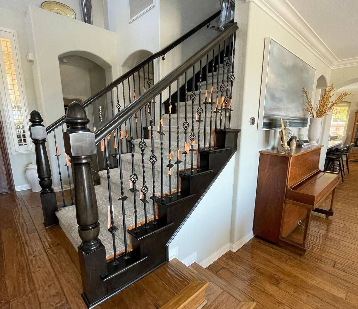 Dark wooden staircase with wrought iron railing, leading to an upper level, in a home.