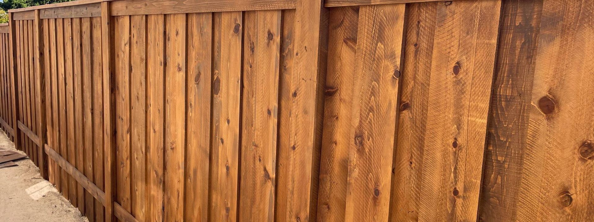 Wooden fence, brown, with vertical planks, outdoors in natural light.