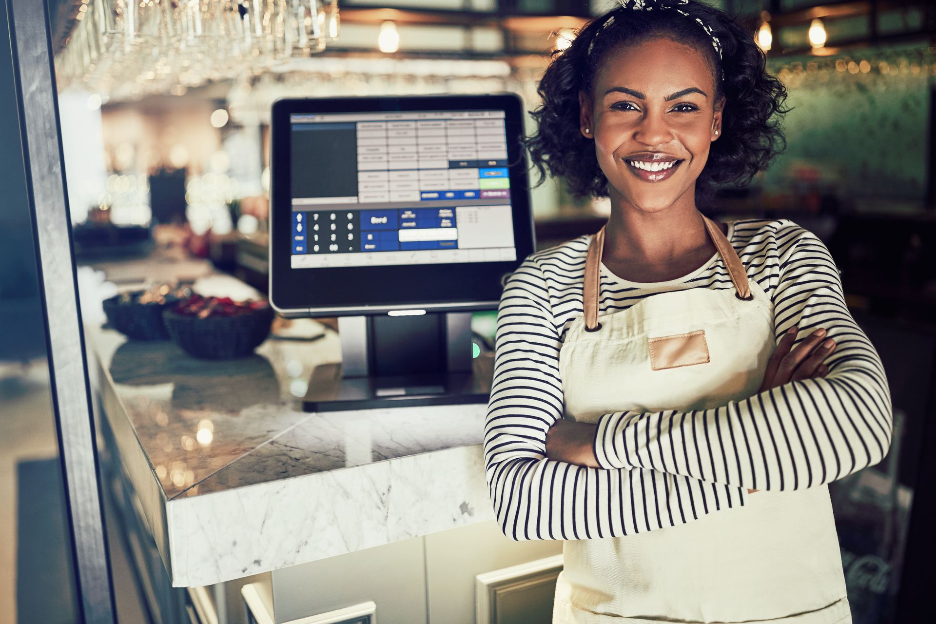 a woman in an apron stands in front of a cash register