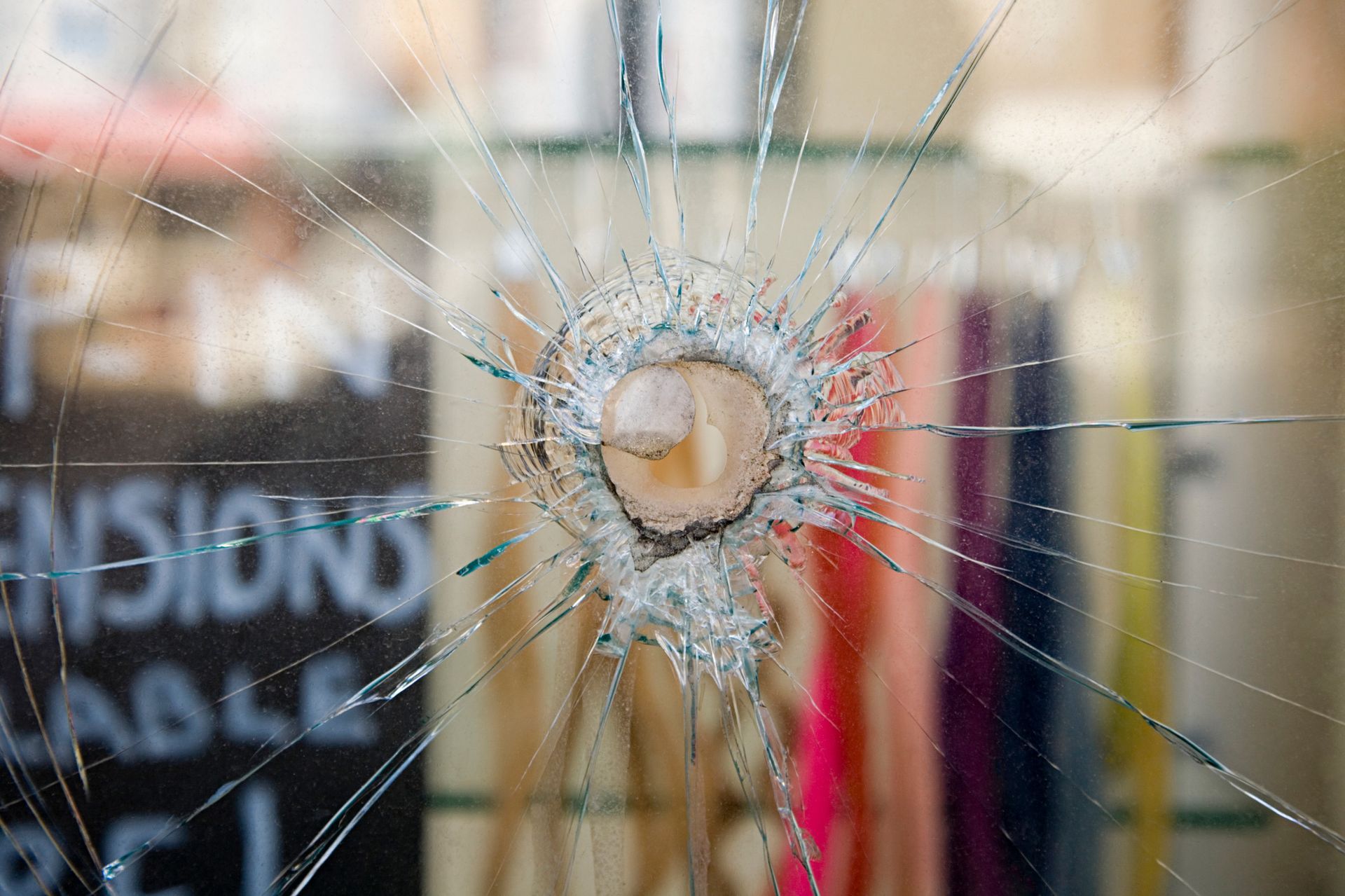 A close-up of a hand of a person inspecting glass window damage.